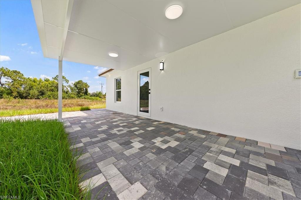 Covered patio featuring multi-tone paver flooring, white stucco exterior, and recessed lighting