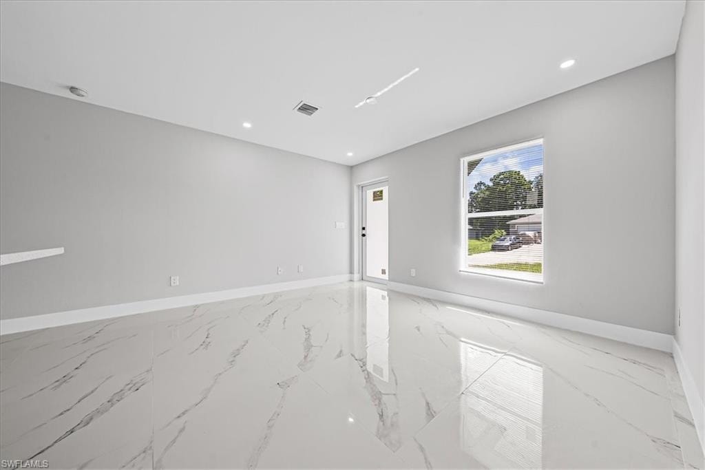 Spacious room featuring large format tile flooring, recessed lighting, a single window, and a white door with black hardware