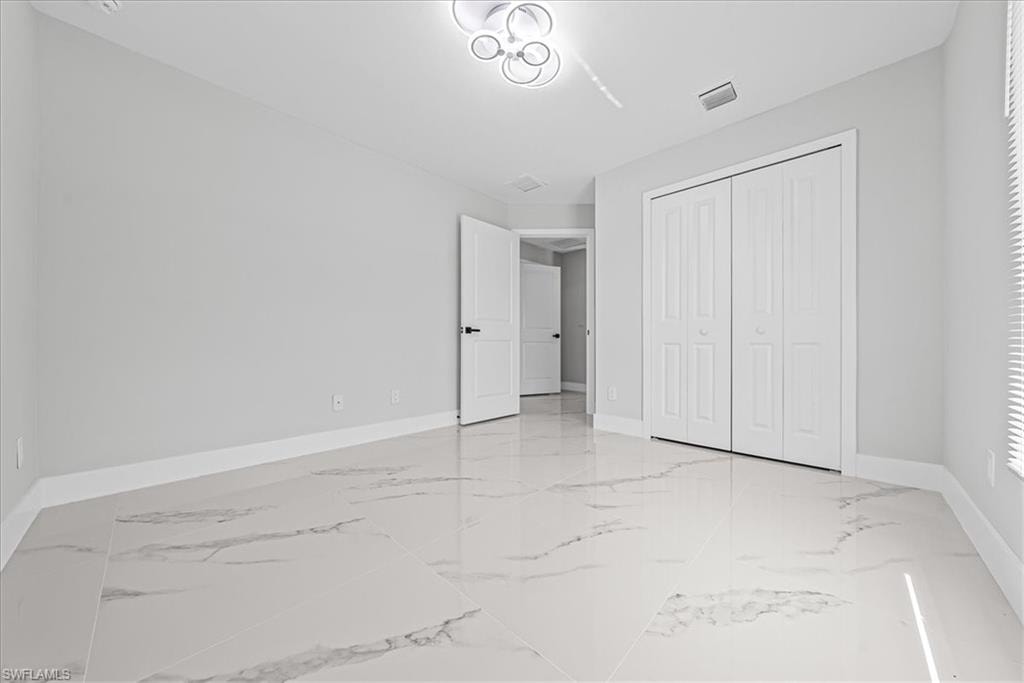 Spacious room featuring large format tile flooring, modern ceiling light fixture, bi-fold closet doors, and recessed lighting