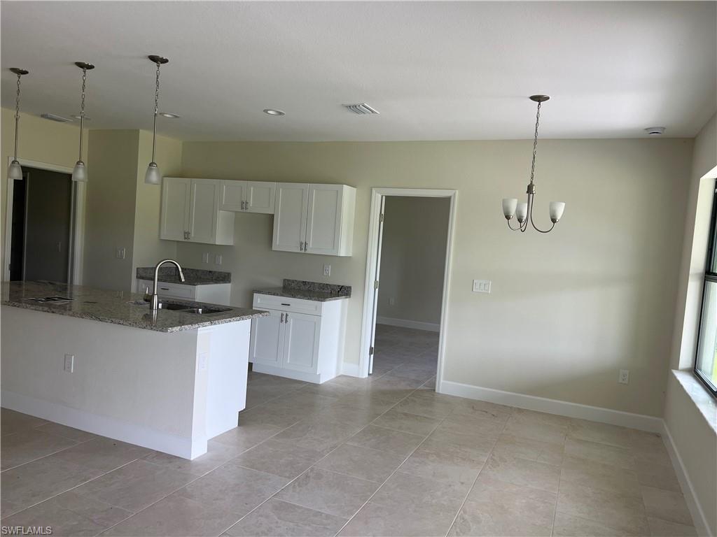Kitchen featuring white cabinetry, granite countertops, a stainless steel sink with a gooseneck faucet, and recessed lighting