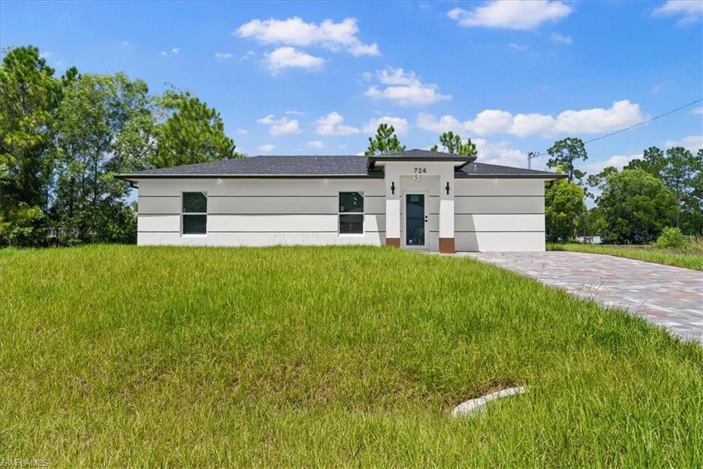 Contemporary architectural style featuring a dark shingle roof, white exterior with gray banding, and a paver driveway
