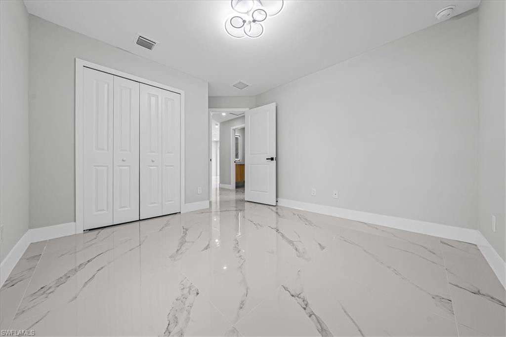 Spacious room featuring large format tile flooring, a contemporary ceiling light fixture, and bifold closet doors