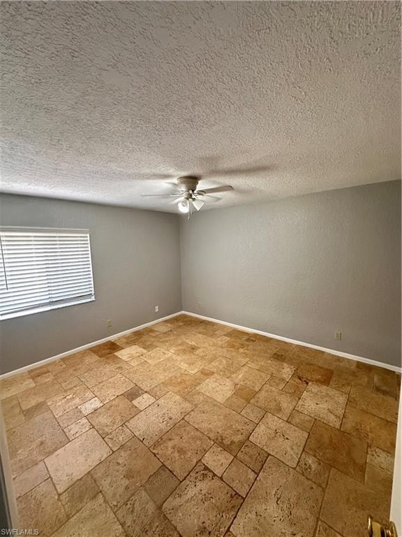 Empty room featuring light tile patterned flooring, a textured ceiling, and ceiling fan