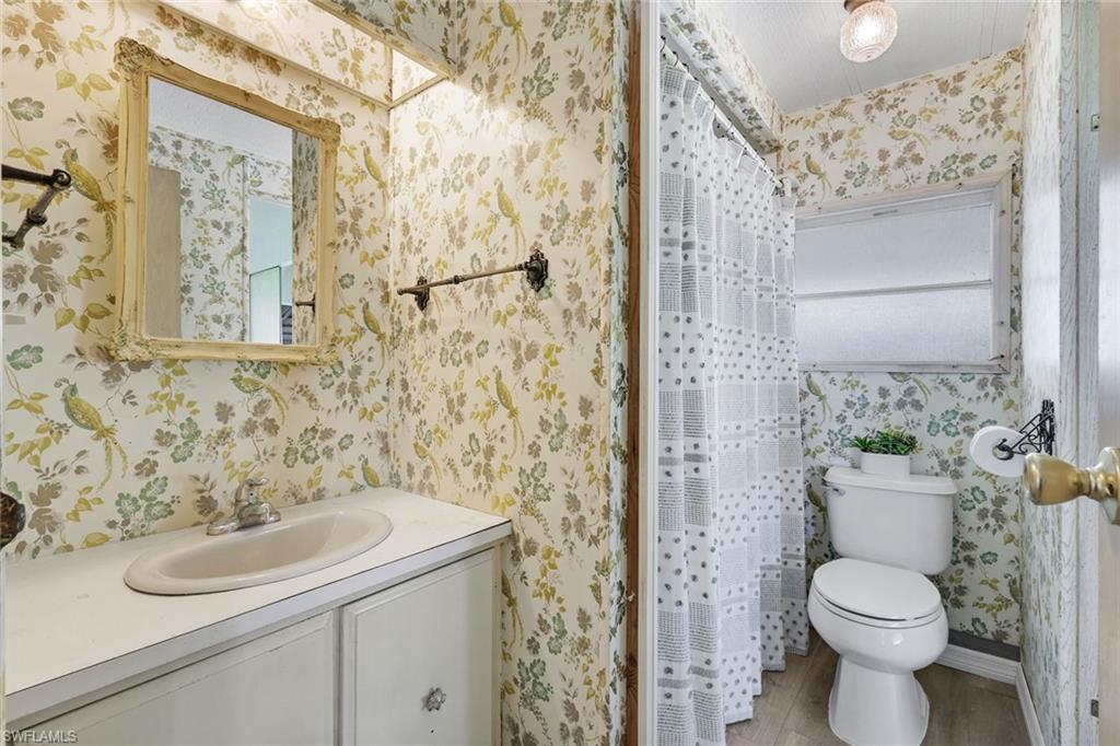 Bathroom featuring a vanity with an integrated sink, a framed mirror, a toilet, and a window for natural light