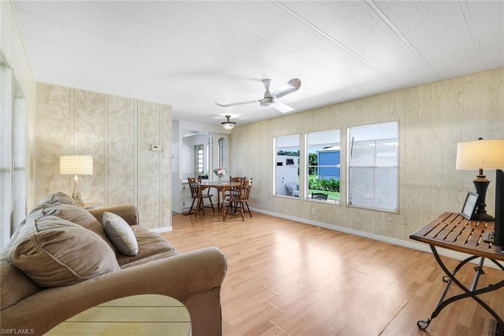 Open-concept living space featuring wood-finish flooring, multiple windows, and a ceiling fan