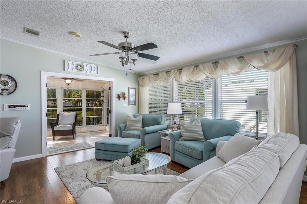 Wood-look flooring throughout, ceiling fan with integrated lighting, expansive windows with blinds offer canal views, and a built-in entertainment niche.