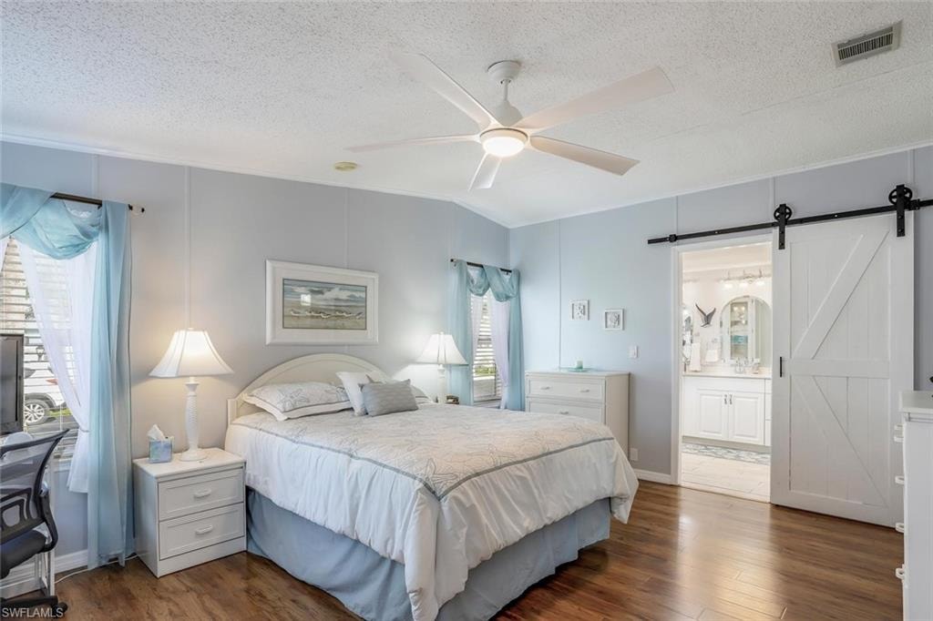 Primary bedroom has ceiling fan with integrated lighting and a sliding barn door to primary bathroom.