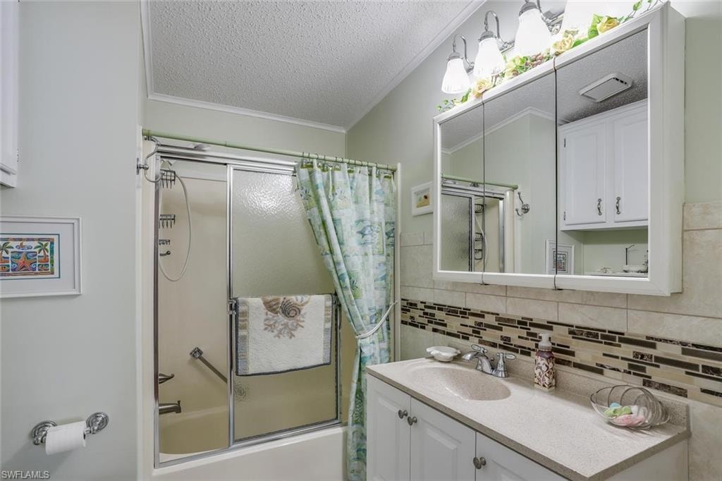 Huge laundry room features white upper cabinetry, tiled countertop,  built-in lower cabinetry with drawers, and a white entry door with decorative glass inlay.