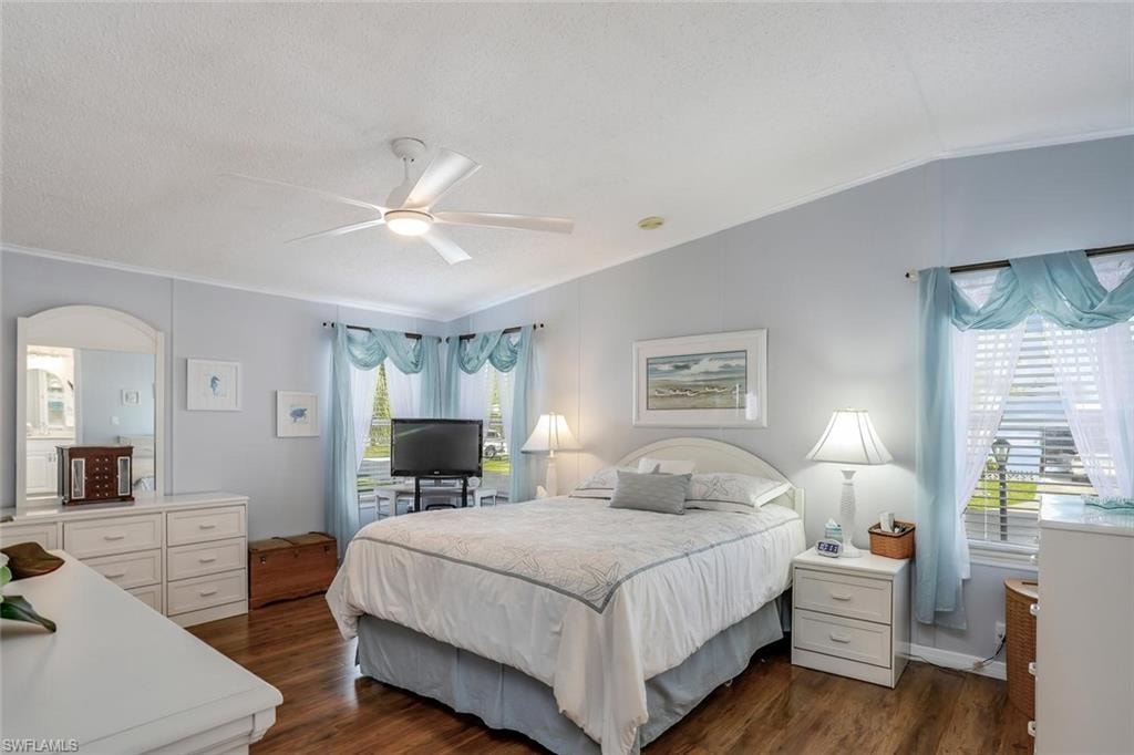 Ceiling fan with integrated lighting, wood-look flooring, lots of windows for natural light, and walk-in closet.