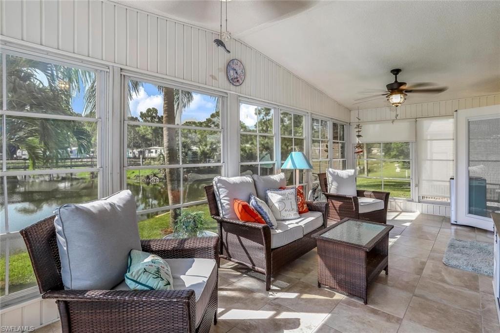 Enclosed Florida Room featuring full-height windows overlooking quiet pond. a vaulted ceiling, and a ceiling fan with integrated lighting.