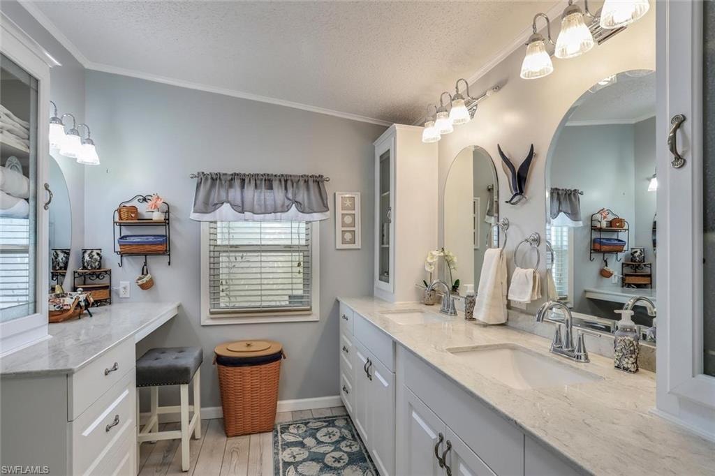 Dual vanity with integrated sinks, quartz countertops, chrome fixtures, light wood look flooring, sun tunnel and a barn door that separates the toilet and shower from the rest of the bathroom.