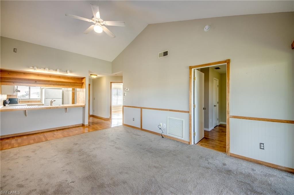 Unfurnished living room featuring light hardwood / wood-style floors, ceiling fan, and high vaulted ceiling