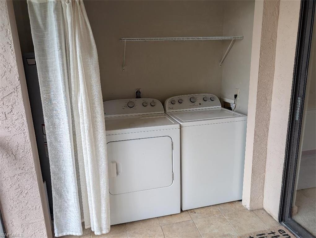 Laundry area featuring washing machine and clothes dryer and light tile patterned floors