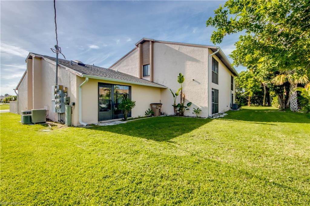 Rear view of property with cooling unit and a yard