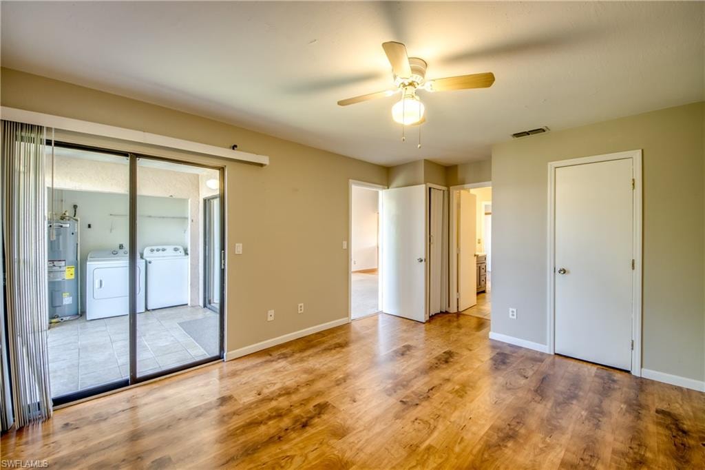 Unfurnished bedroom featuring ceiling fan, multiple windows, light wood-type flooring, and water heater