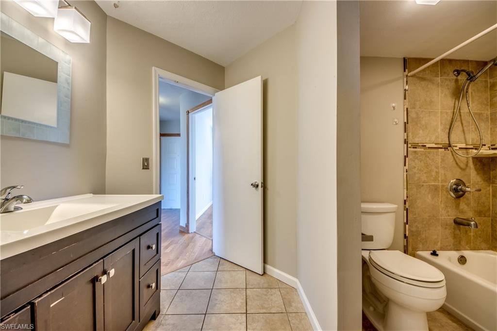 Full bathroom featuring vanity, tiled shower / bath, wood-type flooring, and toilet