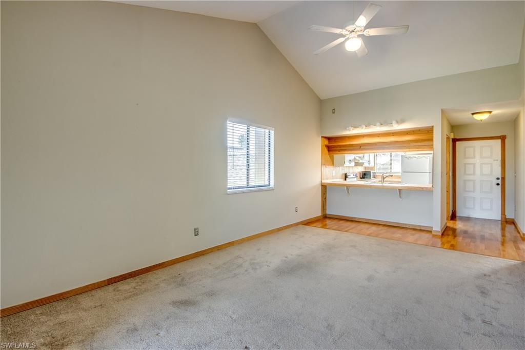 Unfurnished living room featuring sink, high vaulted ceiling, ceiling fan, and hardwood / wood-style flooring