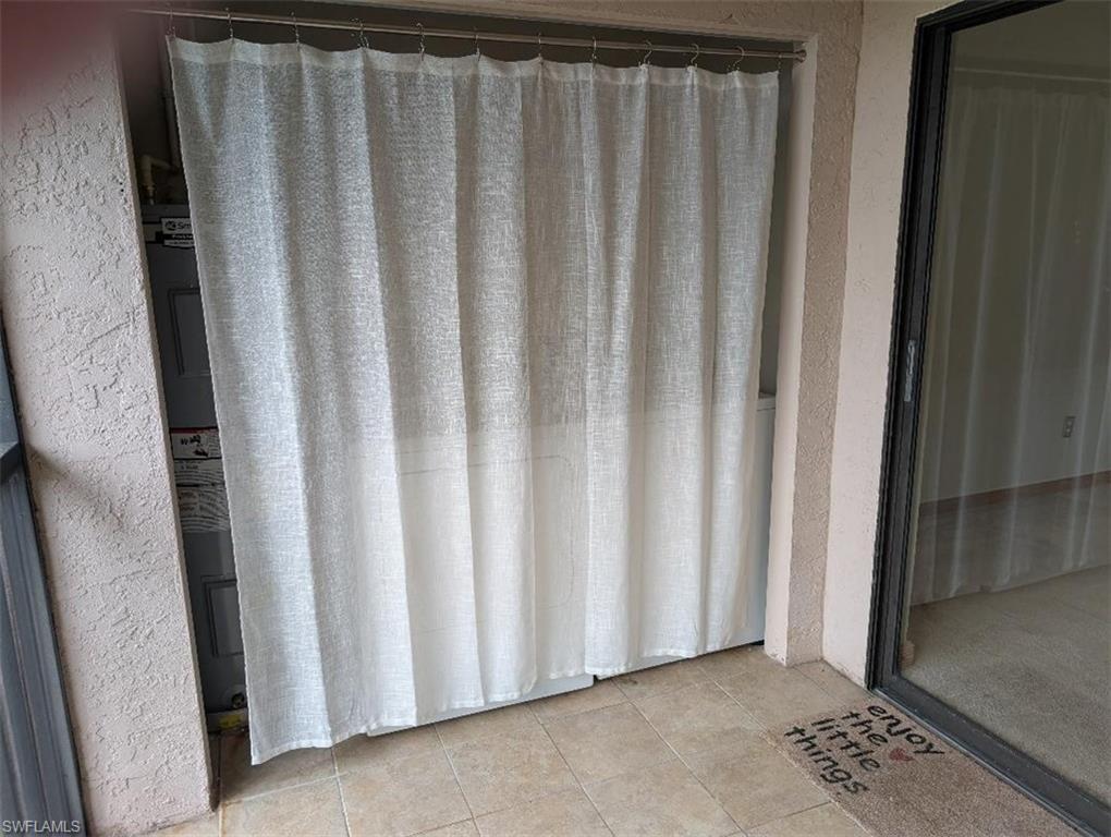 Full bathroom with a stall shower, a textured wall, light tile patterned floors, and electric water heater