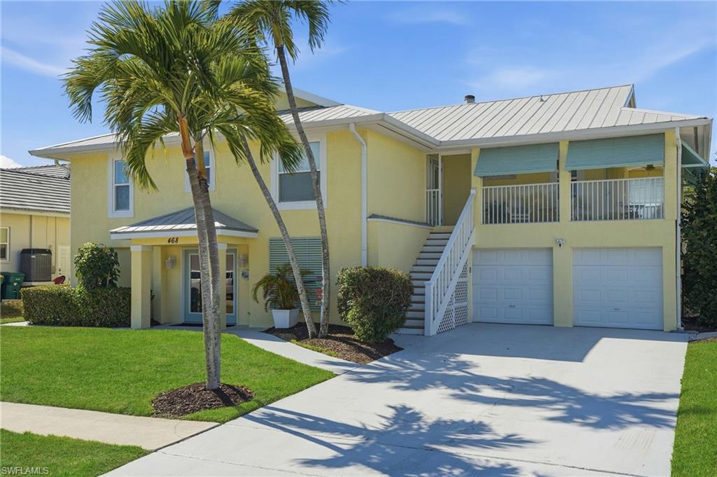 Two-story exterior with a metal roof, an elevated balcony with railing, and a two-car garage