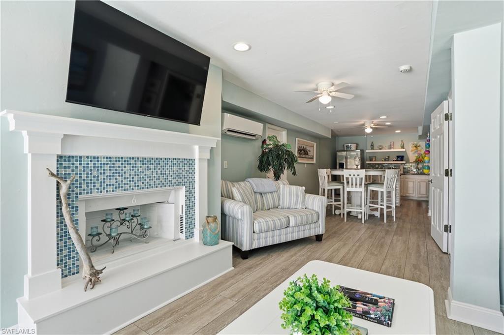 Wood-finish flooring, built-in fireplace with blue tile surround, recessed lighting, and ceiling fans
