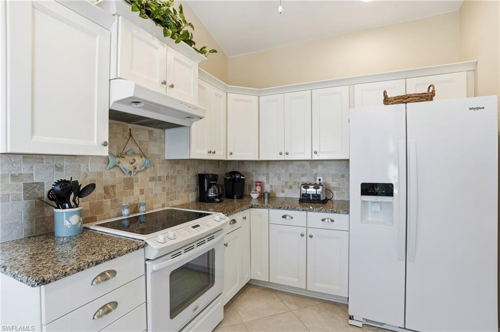 Upstairs main kitchen featuring white cabinetry with polished nickel hardware, granite-finish countertops, tiled backsplash, and recessed lighting
