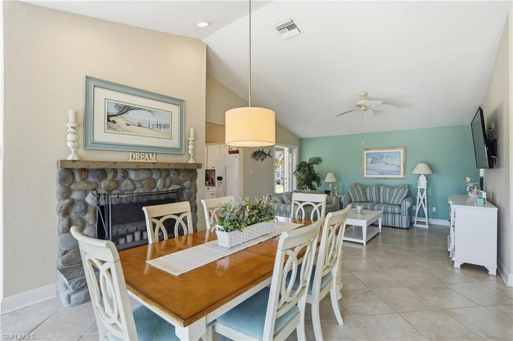 Upstairs dinings area featuring vaulted ceiling, stone-clad fireplace with wood mantel, recessed lighting, ceiling fan, and tile flooring