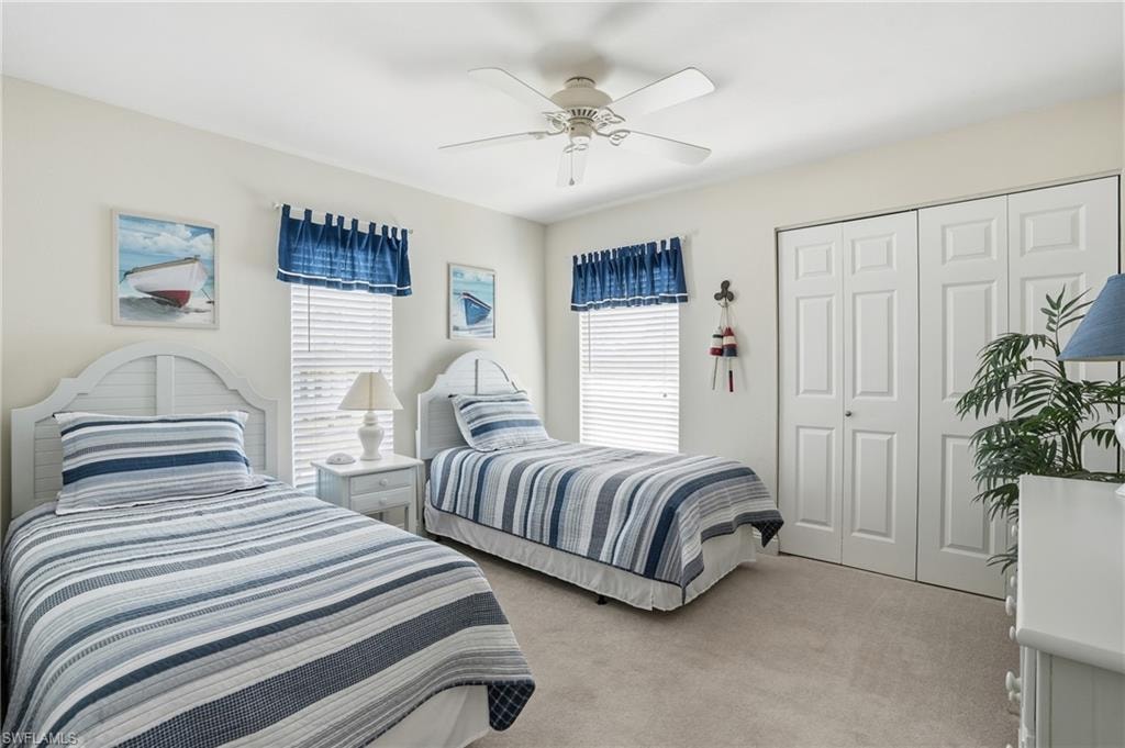 Carpeted flooring, ceiling fan, window with blinds, and white bi-fold closet doors