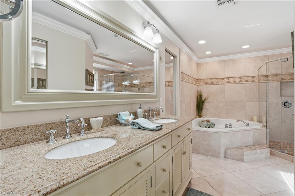 Dual vanity with granite countertop, large framed mirror, recessed lighting, tile flooring, and a built-in jetted tub