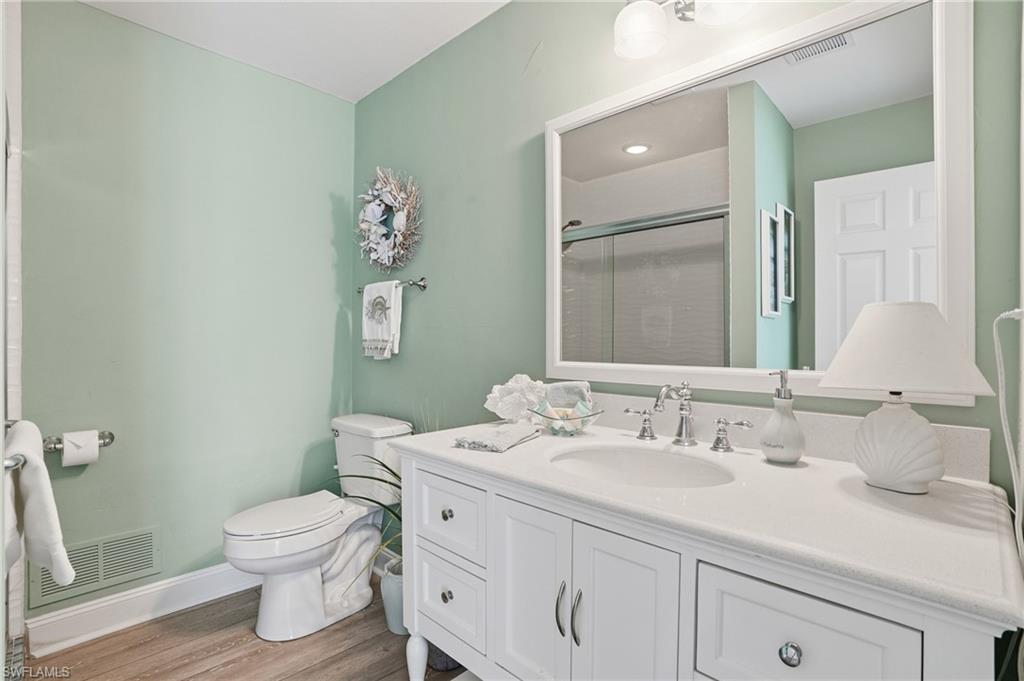 White vanity with cabinet storage, integrated sink, and white countertop