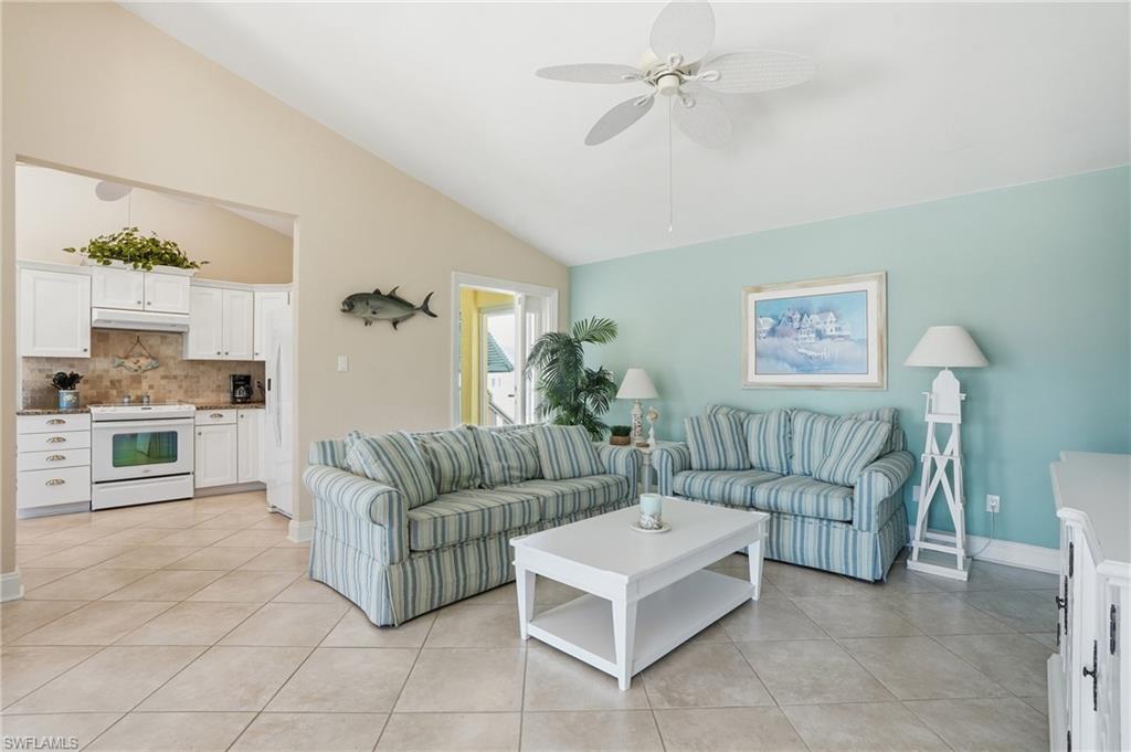Vaulted ceiling with a ceiling fan, light-toned tiled flooring, white cabinetry, white kitchen appliances, and an open concept layout