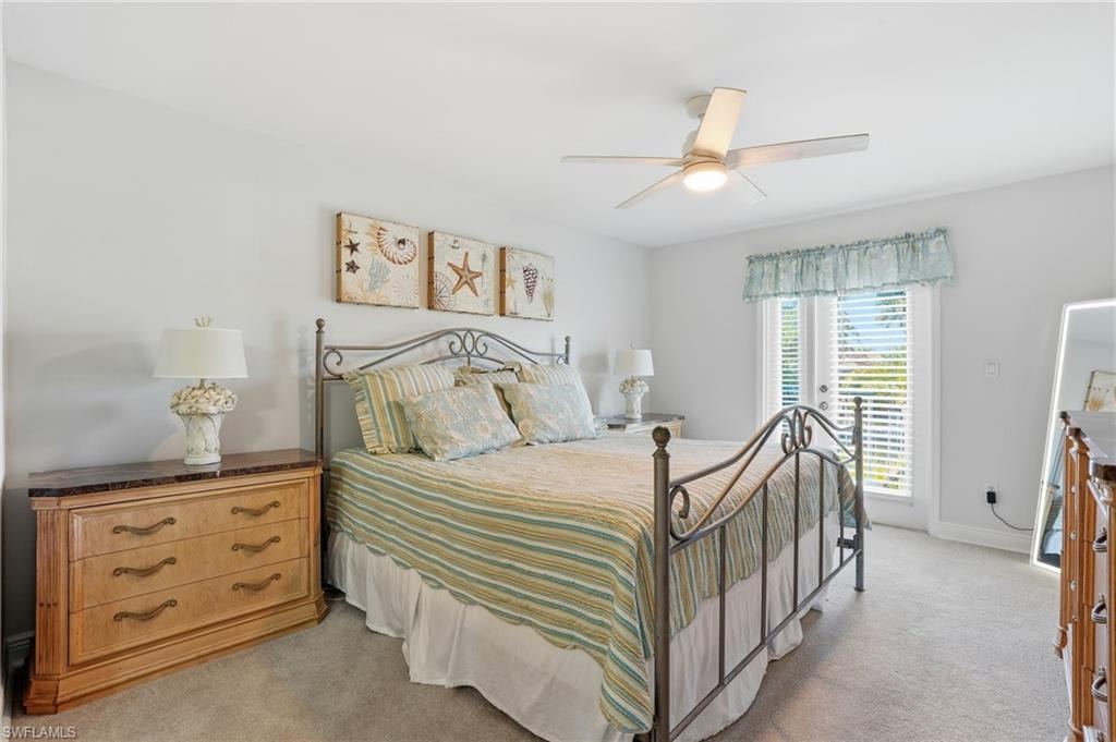 Neutral wall color, ceiling fan, double French doors with interior shutters, and carpeting