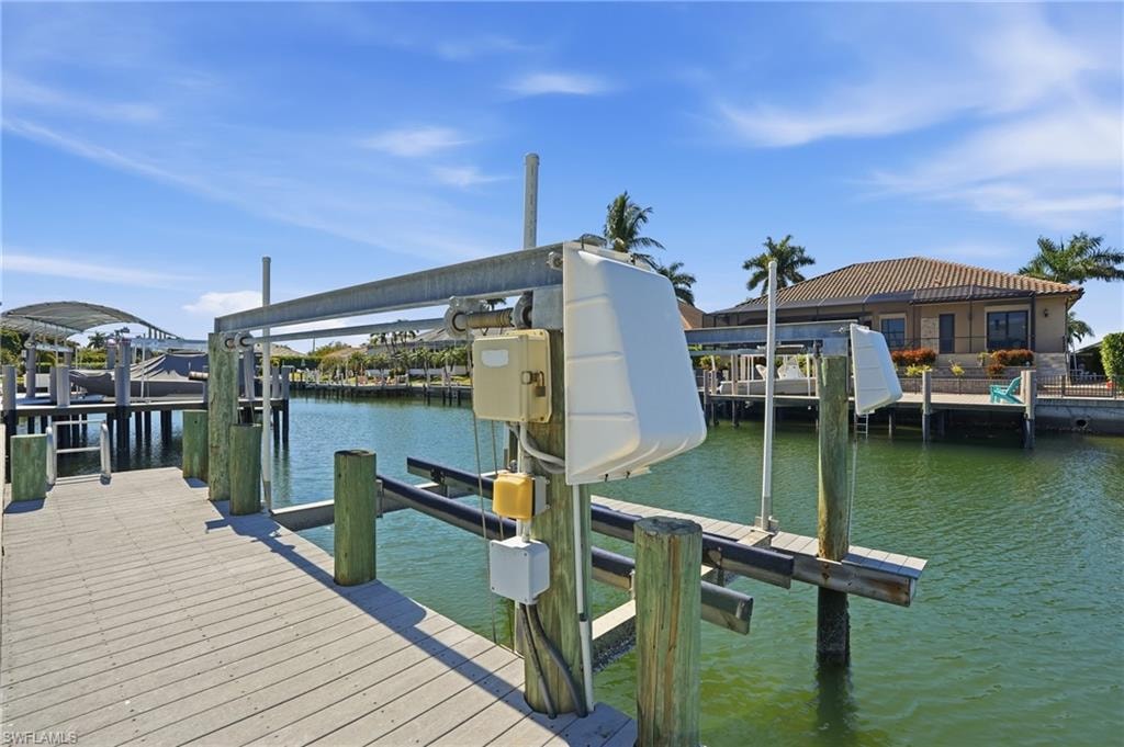 Waterfront property featuring a private boat lift, a wood-finish dock, and direct water access