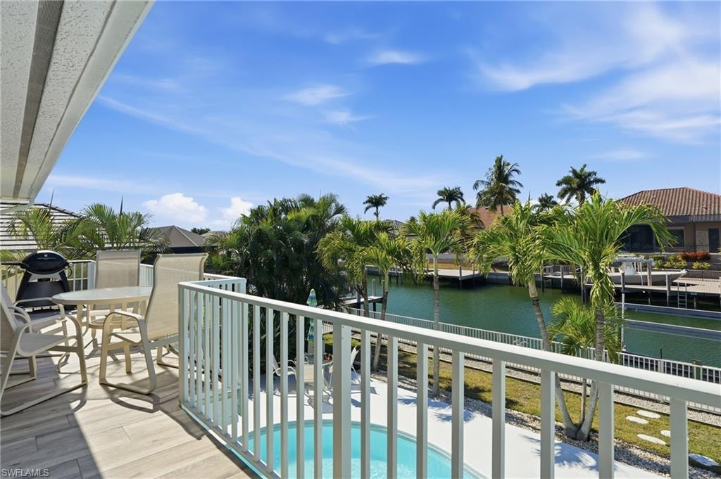 Balcony featuring wood-finish flooring, white railing, and a partial pool