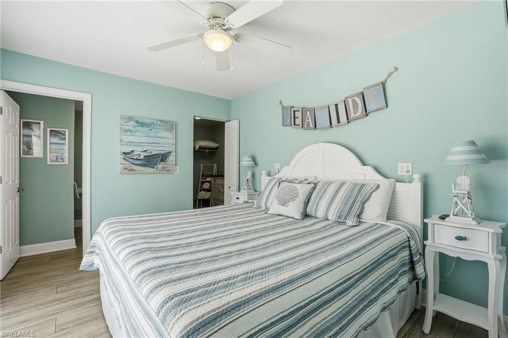 Downstairs Bedroom, Wood-finish flooring, ceiling fan with integrated lighting, white paneled door, and bi-fold closet doors