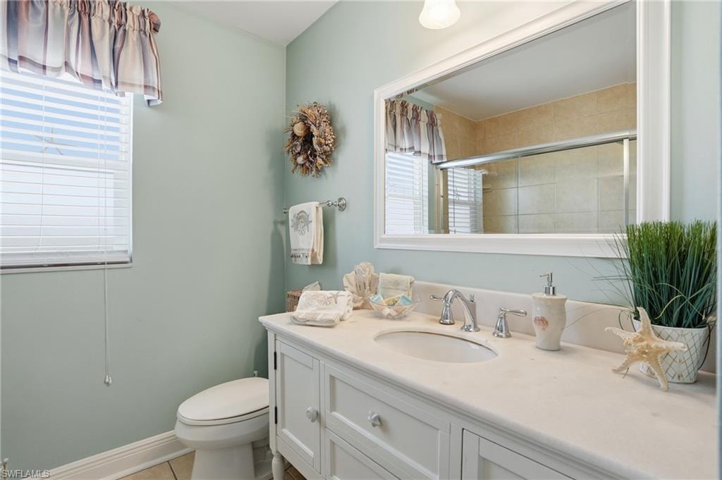 White vanity with an integrated sink and brushed nickel faucet, large framed mirror, and tiled shower enclosure