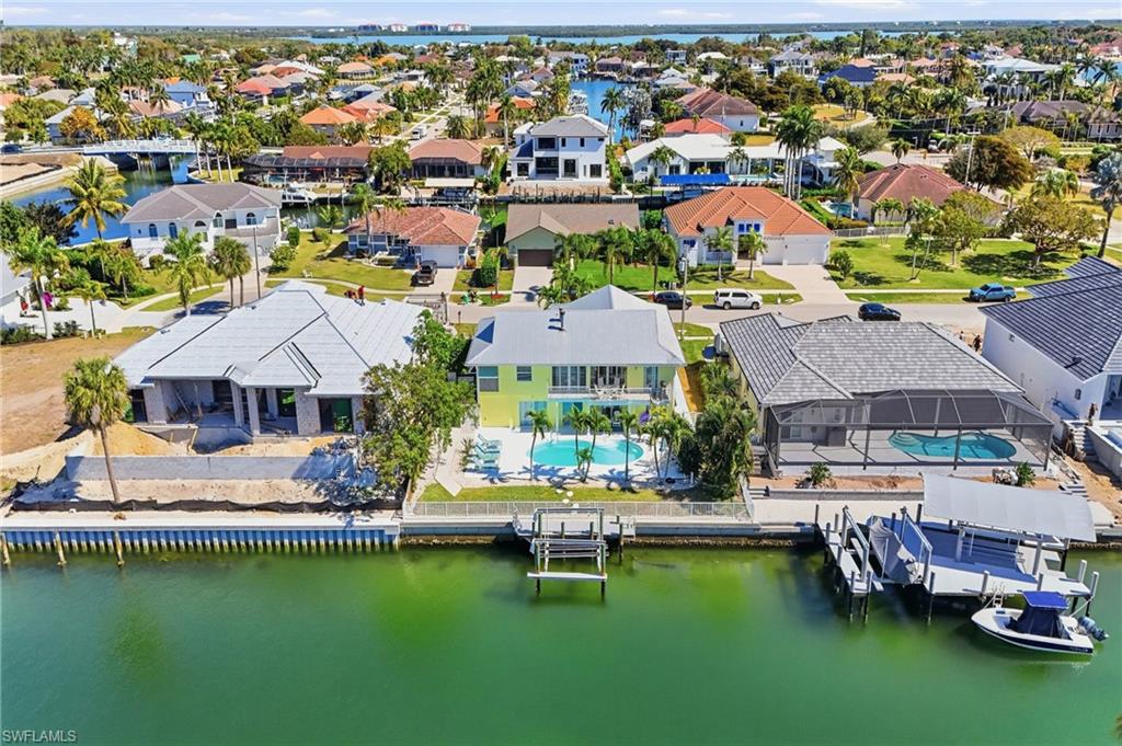 Waterfront residence featuring a resort-style saltwater pool with integrated spa, mature landscaping, and direct canal access with boat dock