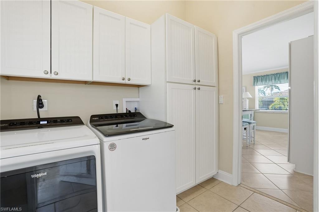 Laundry area with tile flooring and multiple built-in white storage cabinets