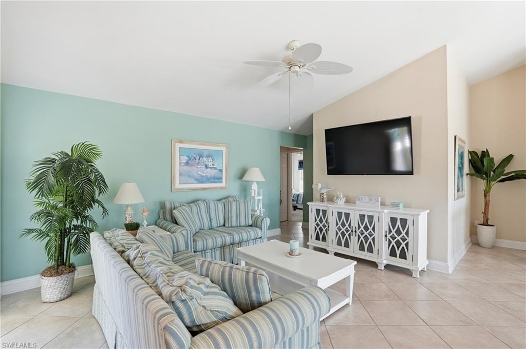 Vaulted ceiling with a ceiling fan, neutral tile flooring, and a built-in media console