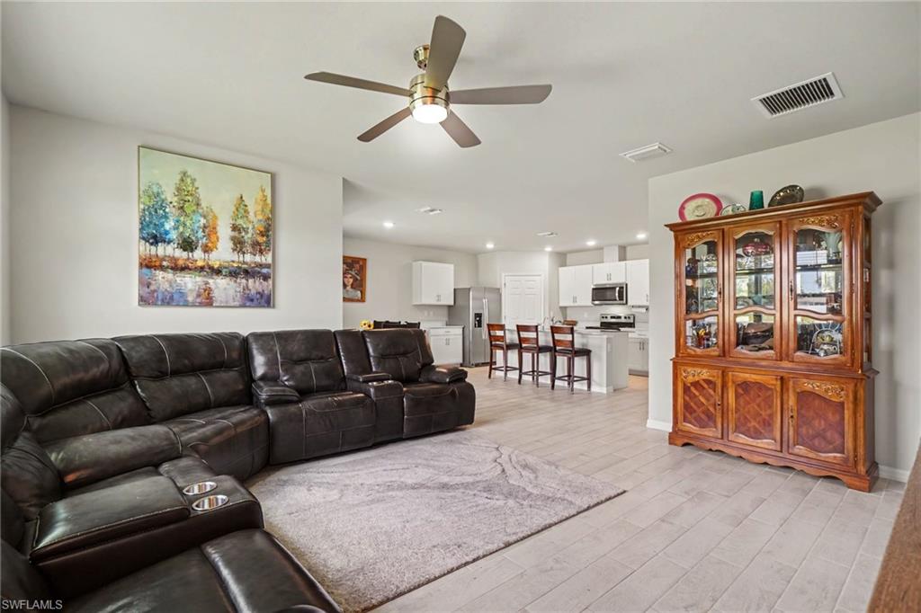 Open-concept living space featuring wood-finish flooring, a ceiling fan with integrated lighting, and recessed lighting