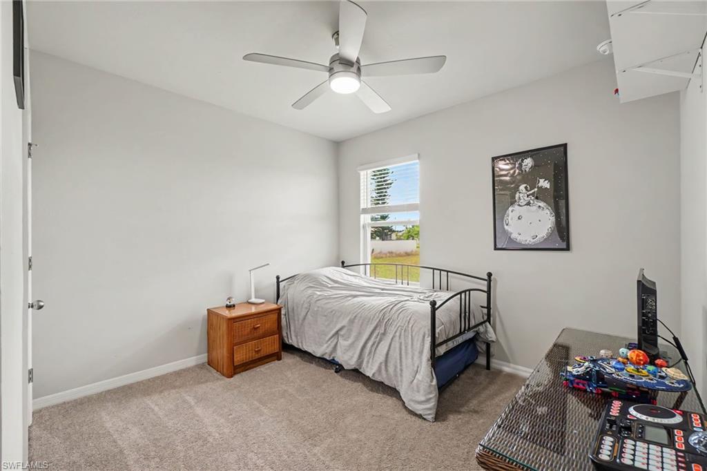 Carpeted flooring, a window with horizontal blinds, and a ceiling fan with integrated lighting