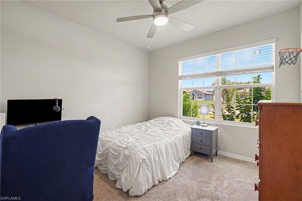 Vaulted ceiling, ceiling fan with integrated lighting, large window with horizontal blinds, and carpeted flooring