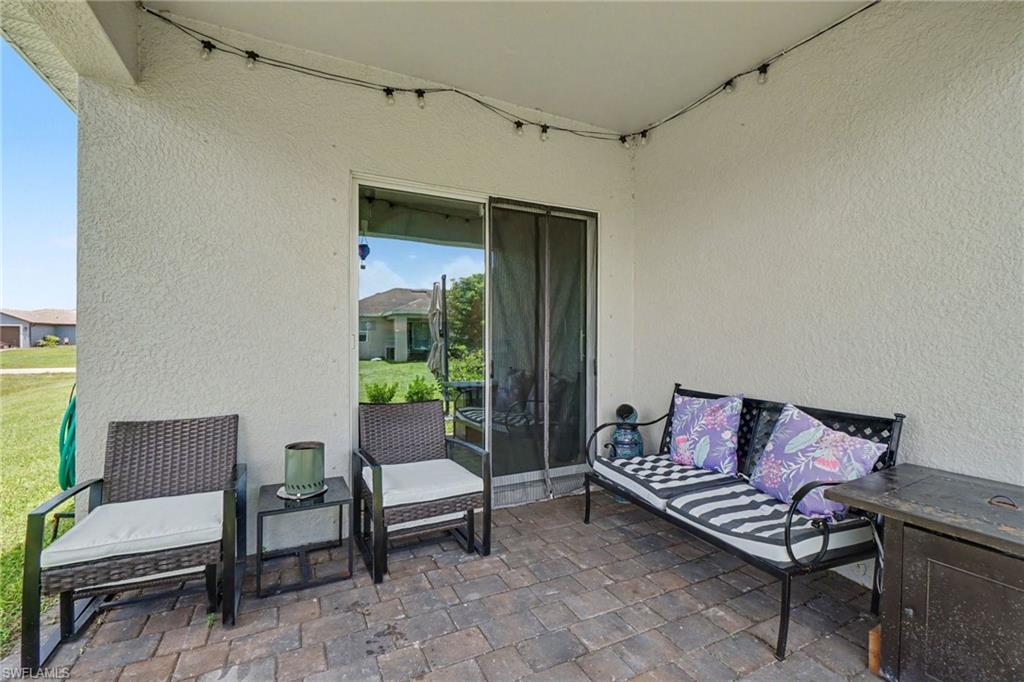 Covered patio with textured stucco walls, paver flooring, and sliding glass door