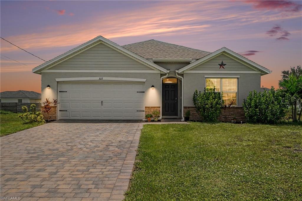 Stucco exterior with beautiful decorative stone accents, a single-car garage, an arched entry, and a paver driveway