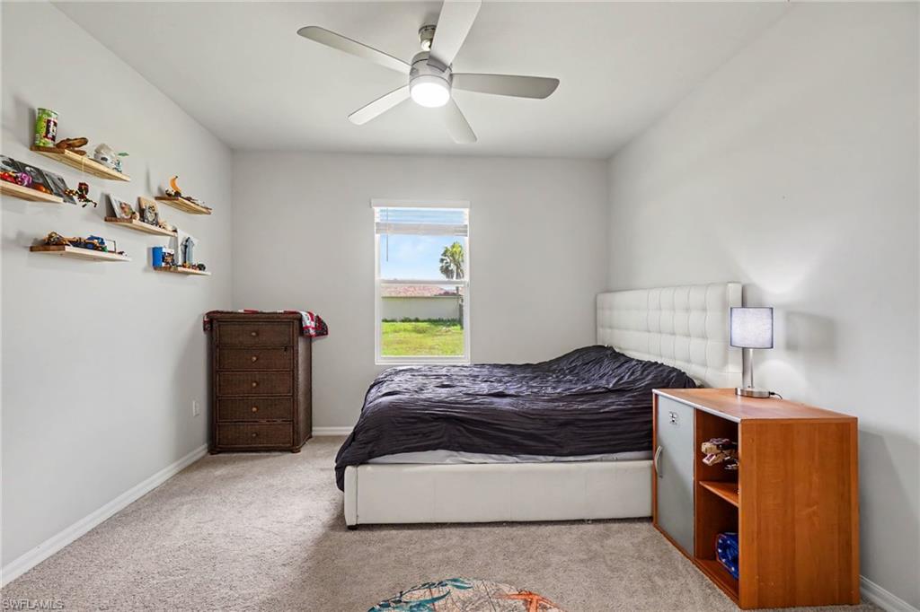 Recessed window with exterior views, ceiling fan with integrated lighting, and neutral carpeting