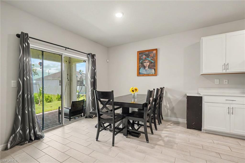 Tiled flooring, white cabinetry, a light countertop, and glass sliding doors leading to a paved patio