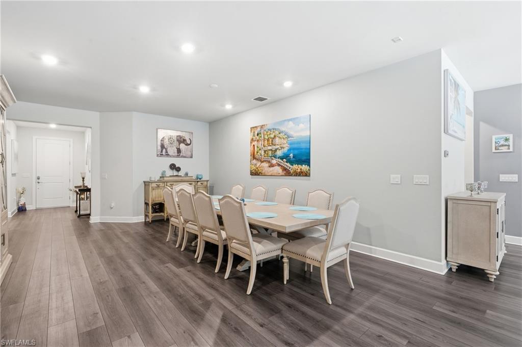 Recessed lighting, wood-finish flooring, white trim, and a white paneled door