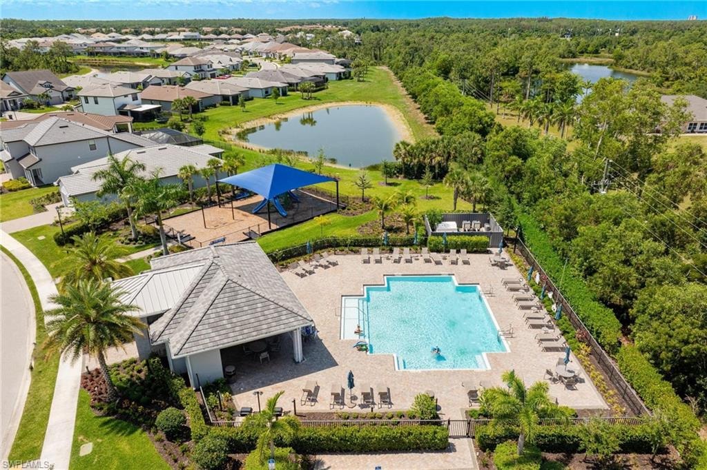 Community pool with surrounding lounge seating, adjacent covered pavilion, and nearby shaded playground area