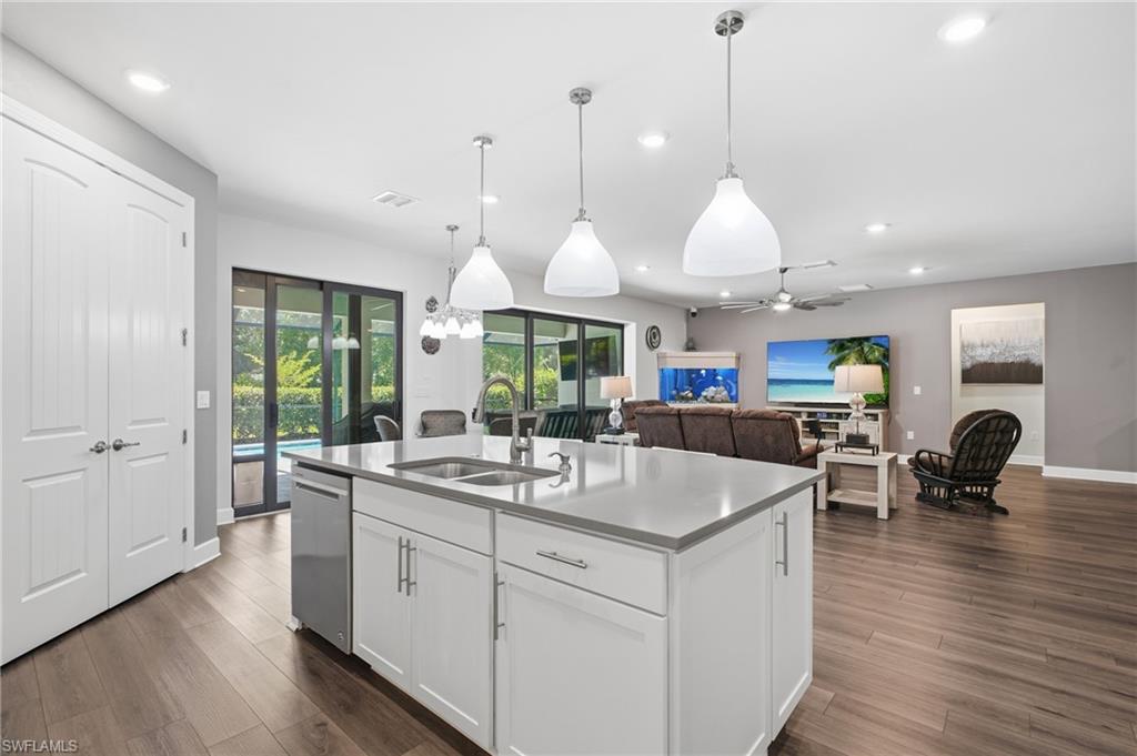 Kitchen island with integrated stainless steel sink, pendant lighting, and white cabinetry