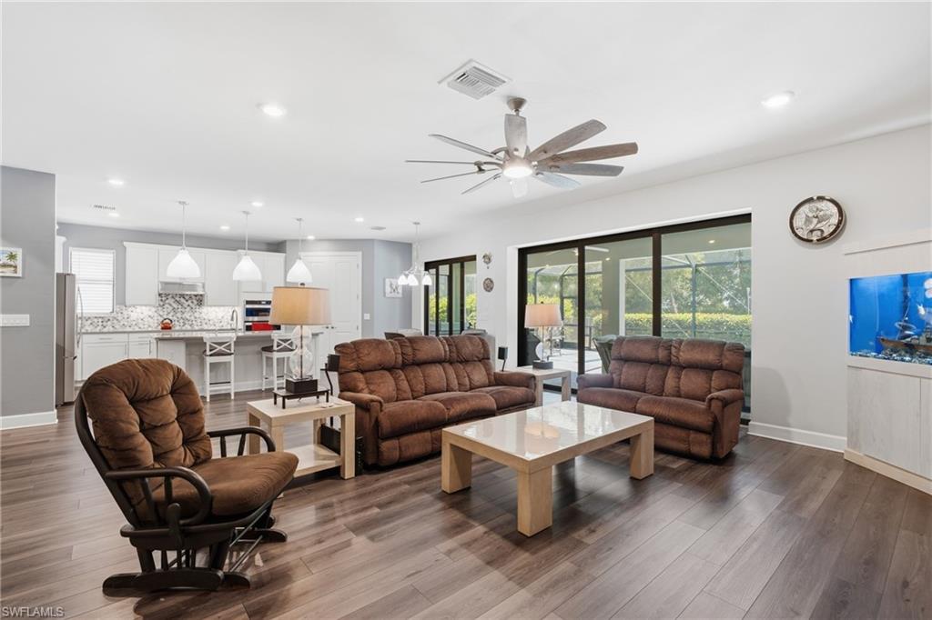 Open-concept living space with wood-finish flooring, white cabinetry, a kitchen island, and sliding glass doors