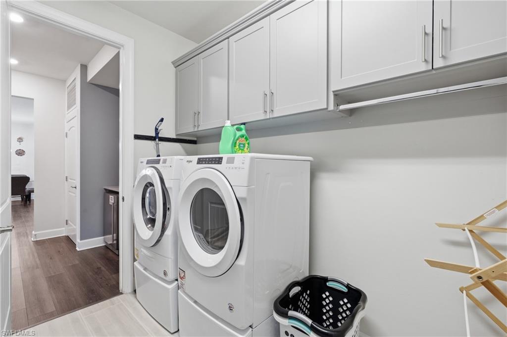 Laundry area featuring light gray shaker-style cabinetry, a built-in hanging rod, and light tile flooring